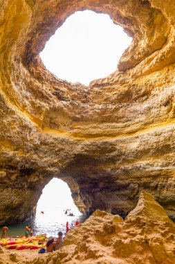 Algarve, Portekiz - 26 Ağustos 2023: Benagil mağarasını ziyaret eden insanlar. Güzel mekan plajıyla ünlüdür ve ışık çatıdaki büyük bir delikten gelir..