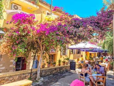 Chania, Girit, Yunanistan - 23 Temmuz 2022: İnsanlar şehir merkezindeki teras restoranlarında yazın keyfini çıkarıyorlar. Eski kentin merkez kısmının adı Kasteli 'dir ve Neolitik çağlardan beri yaşamaktadır..