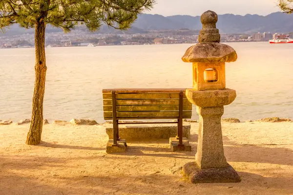 Steinlaterne Und Bank Auf Der Insel Miyajima Während Eines Sonnenuntergangs lizenzfreie Stockfotos