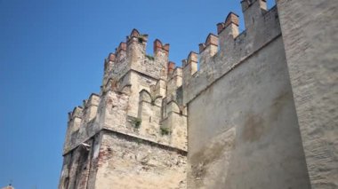 Sirmione, İtalya - 21 Temmuz 2024 Sirmione Kalesi 'nin önünden geçen insanlar. Bina, Garda Gölü 'nün alt kısımlarını ayıran Sirmio yarımadasında yer almaktadır..