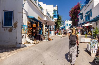 Sidi Bou Said, Kartaca, Tunus - 27 Ağustos 2022: Şehir merkezinde yürüyen insanlar. Kasaba turistik bir yerdir ve mavi ve beyazı yoğun kullanımıyla ünlüdür..