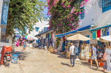 Sidi Bou Said, Kartaca, Tunus - 27 Ağustos 2022: Şehir merkezinde yürüyen insanlar. Kasaba turistik bir yerdir ve mavi ve beyazı yoğun kullanımıyla ünlüdür..