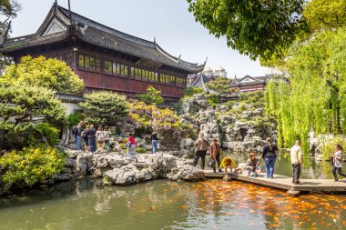 Şangay, Çin - 24 Nisan 2011: Yuyuan Bahçesi 'nde yürüyen insanlar, Şangay' ın tipik bina mimarisinde bir dönüm noktası. Ming Hanedanı döneminde inşa edilen anıt, 1982 yılında ulusal anıt ilan edildi..