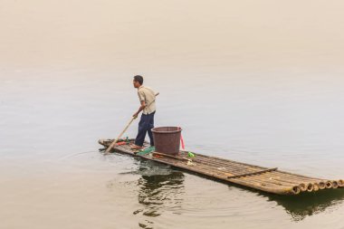 Guilin, Çin - 28 Nisan 2011: Li Nehri 'nde geleneksel karabatak balıkçılığı yapan adam. Bambu salındaki bu geleneksel balık tutma tarzının 1000 yıldan uzun bir tarihi var..