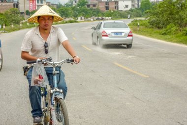 Guilin, Çin - 28 Nisan 2011: Sokakta bisiklet süren adam. Bisiklet sürmek yerel halk ve turistler için yaygın bir ulaşım modudur.
