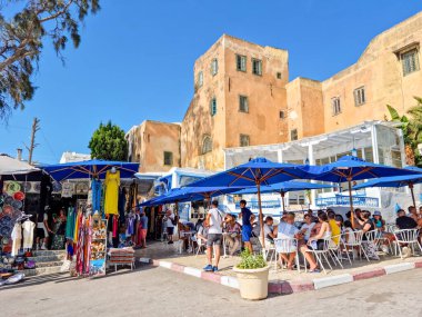 Sidi Bou Said, Kartaca, Tunus - 27 Ağustos 2022: Şehir merkezinde yürüyen insanlar. Kasaba turistik bir yerdir ve mavi ve beyazı yoğun kullanımıyla ünlüdür..