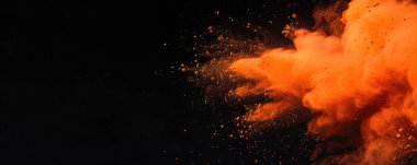 Holi Kutlama Arkaplanı - parlak turuncu bir maddenin yakın çekim görüntüsü, havada toz patlaması gibi görünüyor. Patlama canlı bir turuncu rengi gösteriyor ve parçacıklar çerçevenin her tarafına dağılmış..