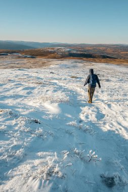 man hiking in beautiful winter landscape snow view from mountain Litjskarven in Norway in sunnlight