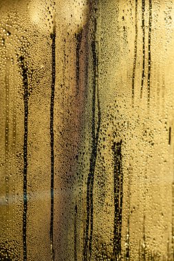 rain drops on window glowing golden abstract background