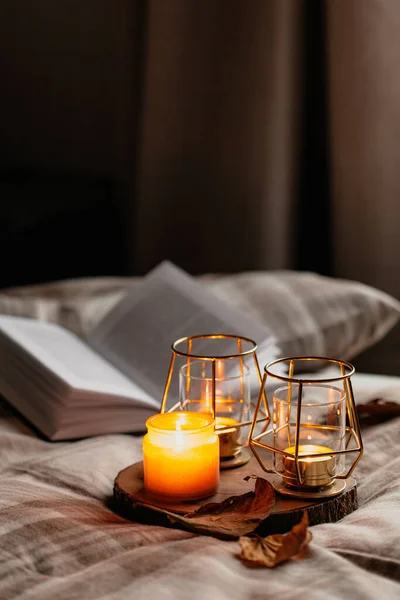 warm cozy bedroom winter or autumn concept, candles on tray and a book