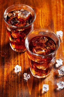 Bir bardak soğuk kola, ahşap zemin üzerinde buz.