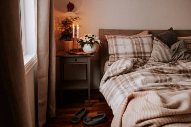 cozy scandinavian bedroom interior in natural tones, blanket candles houseplants