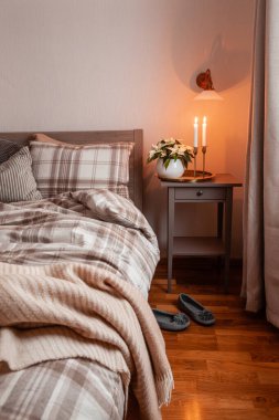 cozy scandinavian bedroom interior in natural tones, blanket candles houseplants