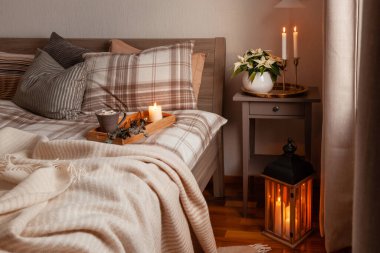 cozy scandinavian bedroom interior in natural tones, blanket candles houseplants