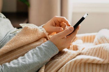 Kafkas bir adam dinleniyor, akıllı telefon kullanıyor. Yatakta yatıyor.