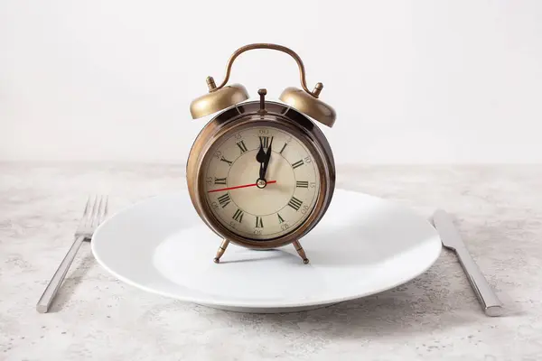 间歇性禁食的概念 产茶饮食 体重减轻 叉子和刀 盘上的闹钟 图库图片