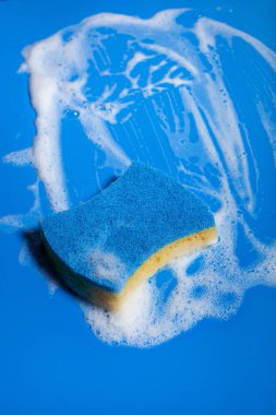 Sünger temizleme köpük sabun köpüğü mavi arka planda, ev yıkama konsepti