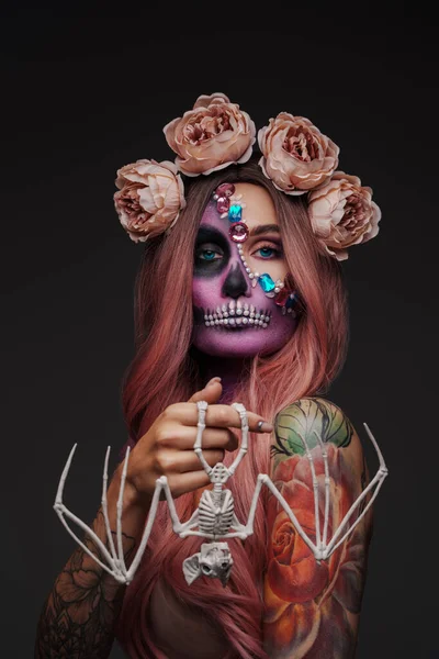 Studio shot of woman with bate skeleton and makeup in mexican muertos style.