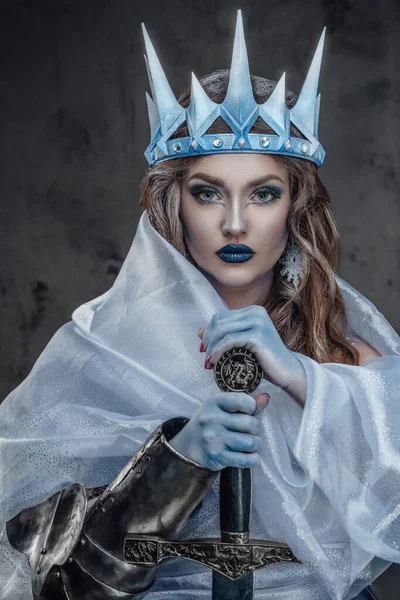 Portrait of ice queen with crown and colden skin holding sword.