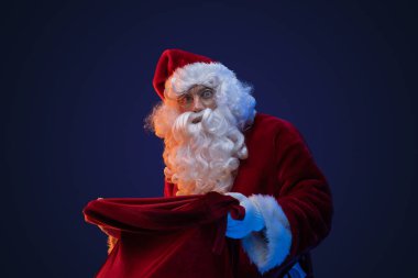 Sakallı Noel Baba 'nın portresi. Kırmızı kostüm ve koyu arkaplanlı çanta..