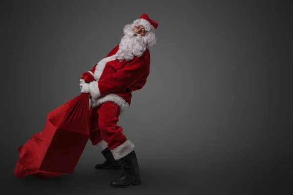 Studio Shot Του Αστεία Santa Claus Σύροντας Μεγάλη Τσάντα Δώρα — Φωτογραφία Αρχείου