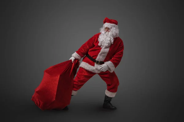 Studio Shot Funny Santa Claus Dragging Big Bag Gifts Gray — Stock Photo, Image