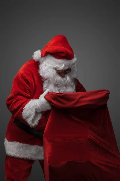 Портрет Ізольованого Сірому Фоні Санти Дивиться Сумку Різдвяними Подарунками — стокове фото