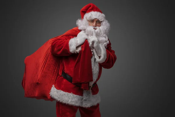 Фото Санта Клауса Мішком Пальцем Губах Сірому Фоні — стокове фото