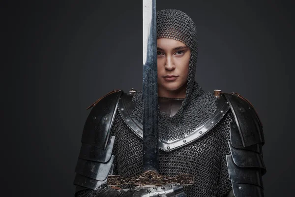 Studio shot of female knight holding sword and looking at camera.