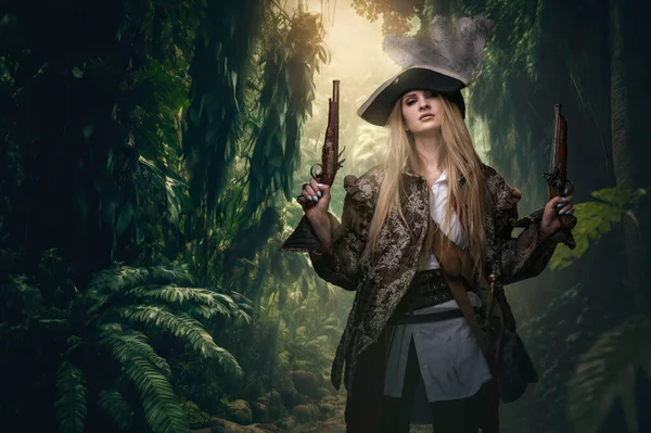 Portrait of buccaneer woman with pistols and hat in jungle of tropical island.