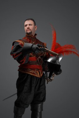 Portrait of conquistador with pistol dressed in red suit looking away.