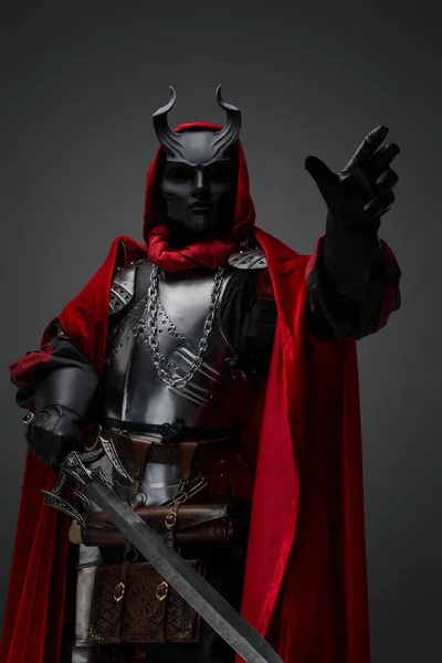 Shot of dark knight with plate armor and red robe armed with sword.
