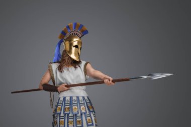 Shot of violent ancient female warrior with spear against grey background.