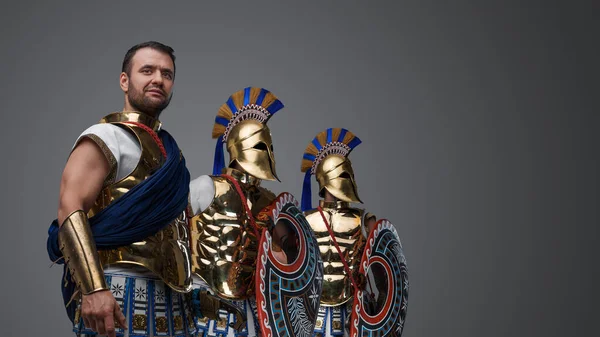 青銅製のプレートの鎧に身を包んだ古代ギリシャのハンサムな3人の戦士のスタジオショット — ストック写真