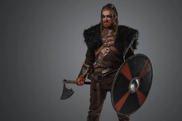 Shot of medieval nordic barbarian with black fur and armor holding axe.