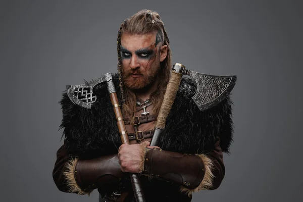 工作室拍摄的可怕的北欧野蛮人与一对斧头和黑色毛皮 — 图库照片