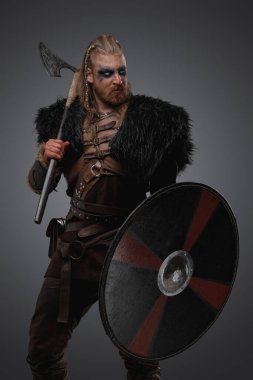 Gri arka planda, siyah kürk tutan kalkan ve baltalı viking stüdyosunun görüntüleri..