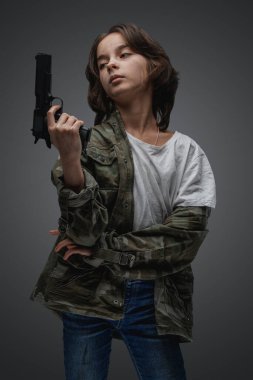 Elinde tabanca olan, kamuflaj ceketi giymiş, kıyamet sonrası cesur genç kızın fotoğrafı..