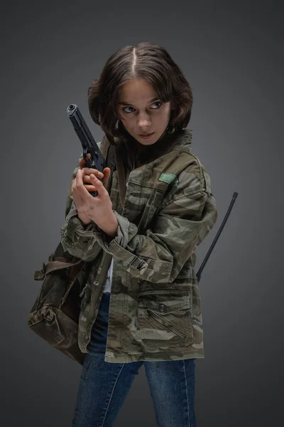 带着迷彩服手持手枪在天灾后场景中幸存的小女孩的画像 — 图库照片