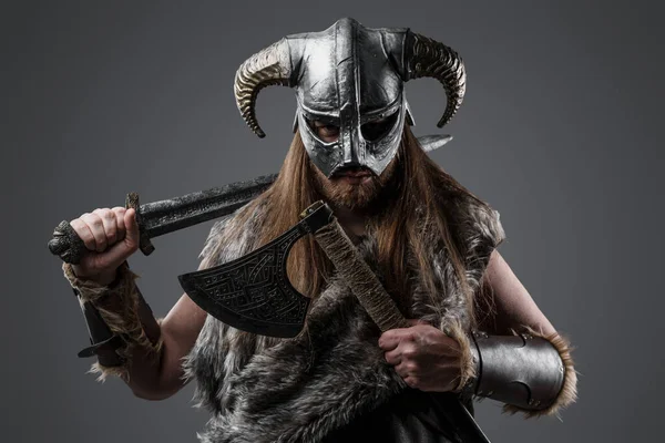 身着毛皮衣服头戴角形头盔拿着剑和斧头的北欧野蛮人的画像 — 图库照片