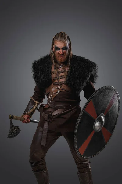 グレーを背景にした革製の鎧や毛皮を着た激怒北欧戦士のショット — ストック写真