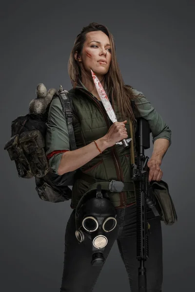銃とナイフを背景にバックパックを運ぶ女性殺人鬼の肖像 — ストック写真