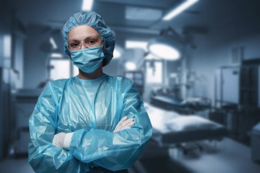 Modern ameliyathaneye karşı çapraz kollarla poz veren cerrah kadın..