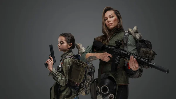 Studio shot of post apocalyptic woman and young girl against gray background.
