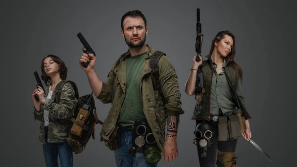 Portrait of three people survivors with guns in post apocalyptic style.