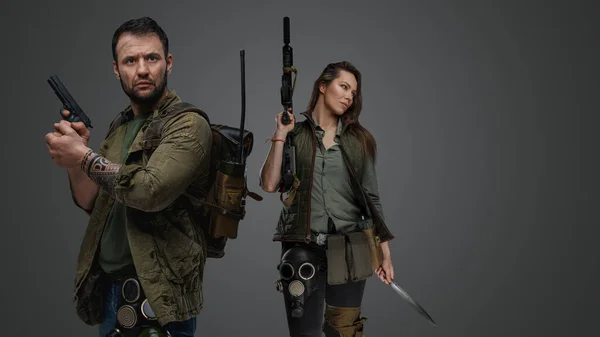 スタジオショットのポスト黙示録的なカップル生存者と銃グレーの背景 — ストック写真