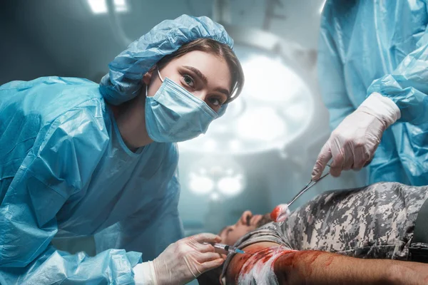 Strzał Lekarzy Leczących Żołnierza Ranną Ręką Nowoczesnej Sali Operacyjnej Kliniki — Zdjęcie stockowe