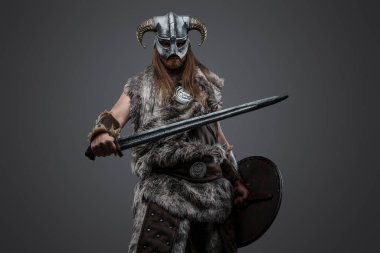 Kürk giymiş ve boynuzlu miğfer takmış gri arka planda eski Viking resimleri..