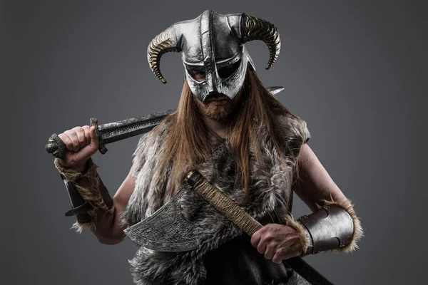 身着毛皮衣服头戴角形头盔拿着剑和斧头的北欧野蛮人的画像 — 图库照片