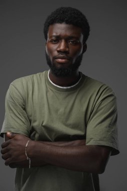 Afrikalı etnik bir adamın portresi. Kameraya bakarak çapraz kollarla poz veriyor..